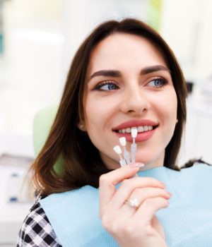 Girl chooses color of veneers at the dentist office Girl chooses color of veneers at the dentist office